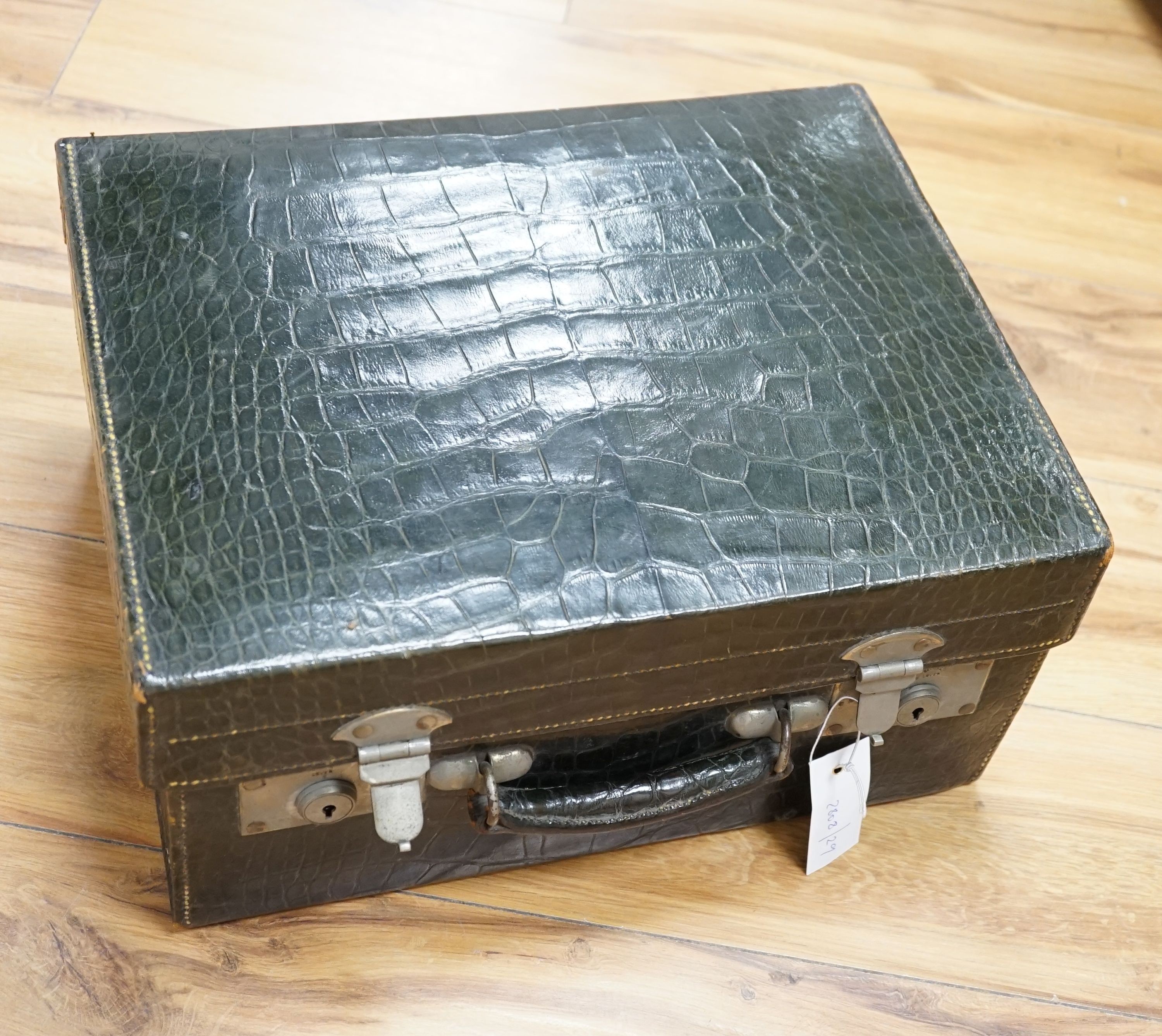 An early 20th century green crocodile toilet case with silver mounted interior, width 39 cms.